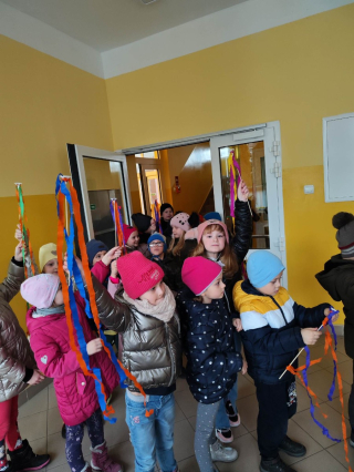 grupa przedszkolaków ubrana na kolorowo trzymająca w rękach kolorowe wstążki
