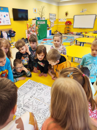grupa przedszkolaków rysująca przy żółtym stoliku