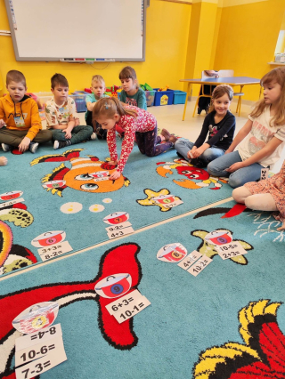 grupa przedszkolaków bawiąca się na kolorowym dywanie