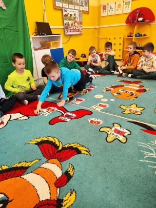 grupa przedszkolaków bawiąca się na kolorowym dywanie
