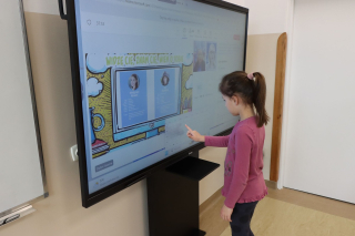 uczennica stojąca przy monitorze interaktywnym i wykonująca ćwiczenie w ramach webinaru