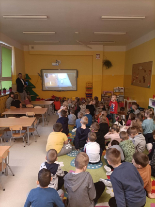 grupa przedszkolaków siedząca na dywanie i oglądająca bajki słowiańskie