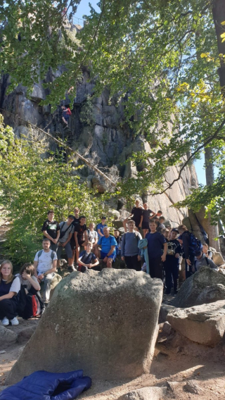 uczniowie z opiekunem odpoczywający na kamieniach na szczycie góry 