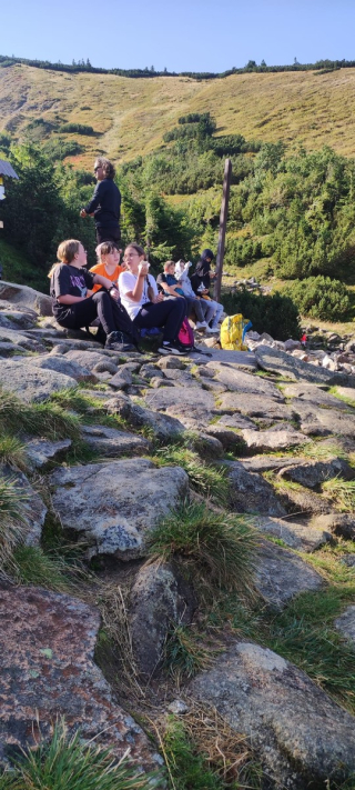 grupa uczennic siedząca na kamieniach, odpoczywająca na szlaku